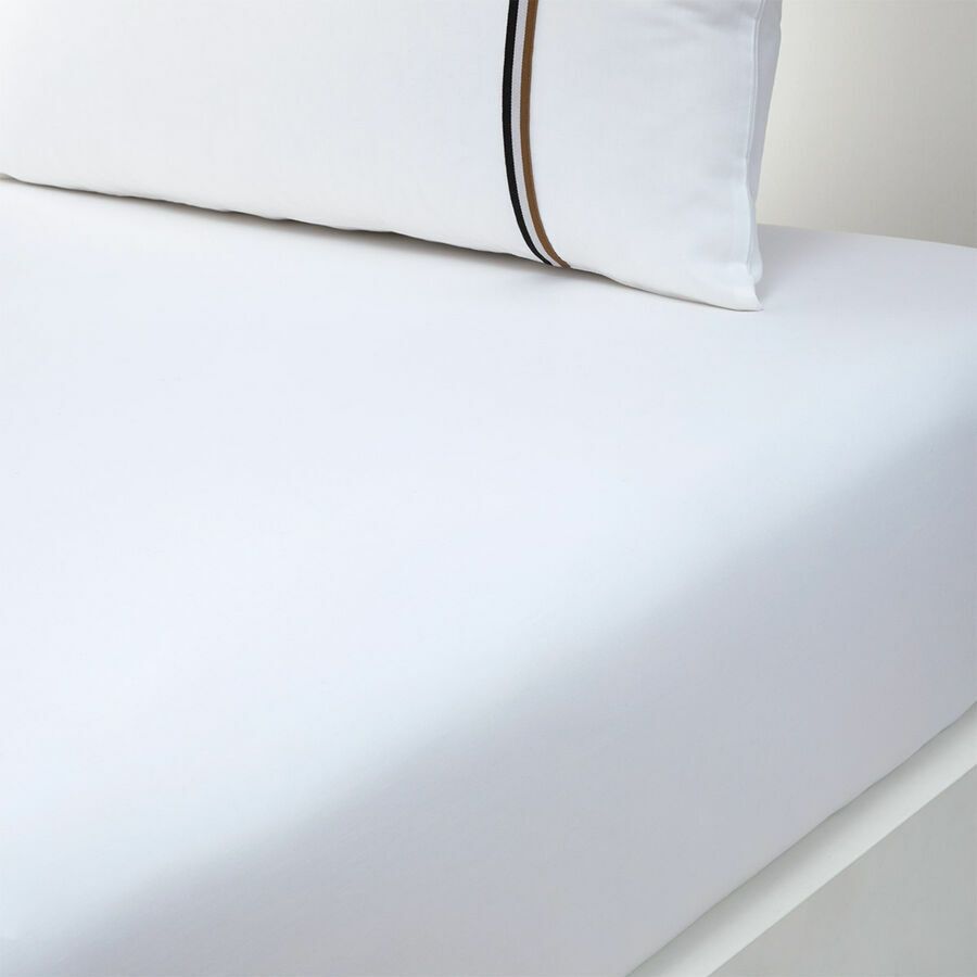 Un lit avec des draps blancs et des oreillers dessus