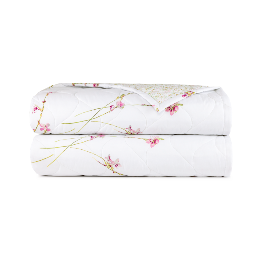 Un couvre-lit blanc matelassé plié en deux, orné d'un délicat motif de fines tiges vertes et de petites fleurs roses.