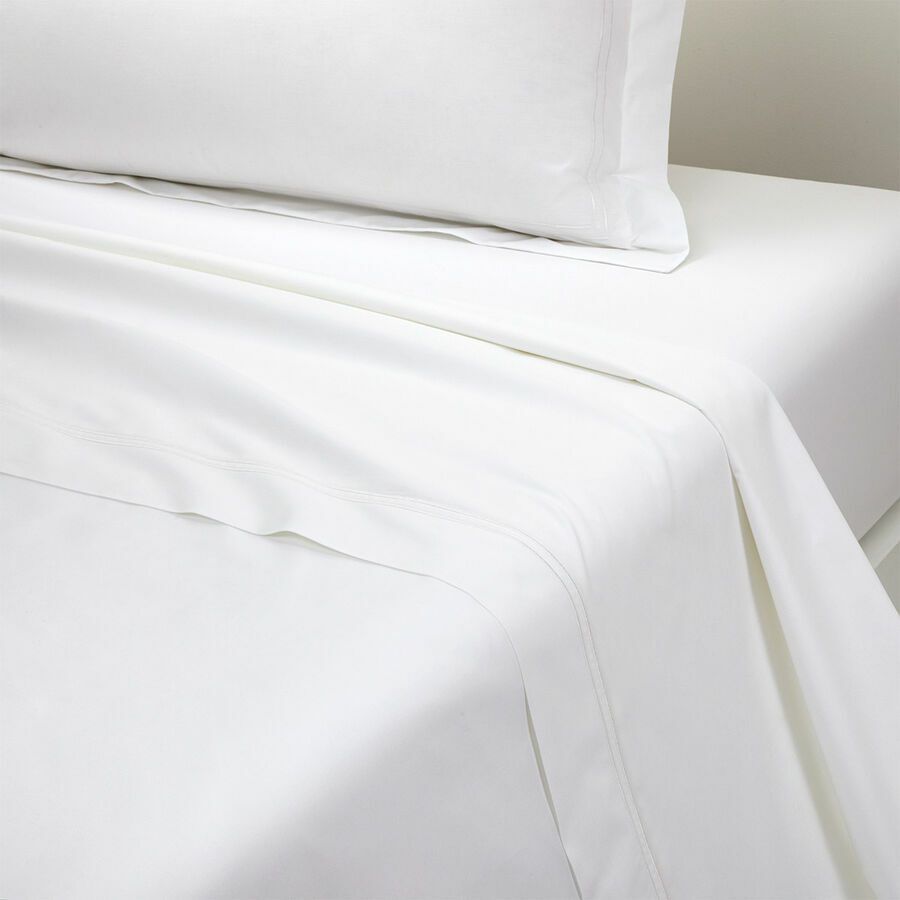 Un lit avec des draps blancs et des oreillers dessus.