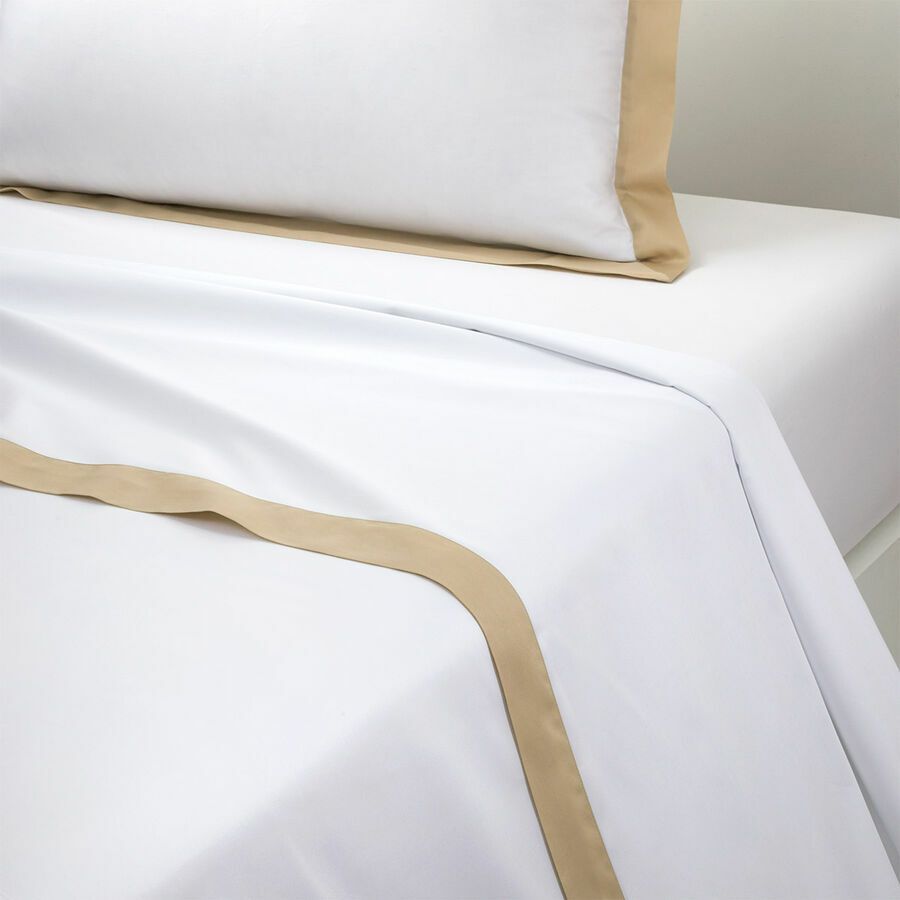 Drap blanc avec bordure beige et oreiller.