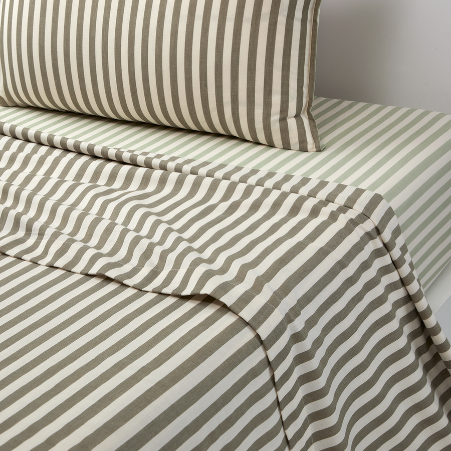 Lit rayé beige et blanc avec oreiller et couverture assortis, soigneusement fait