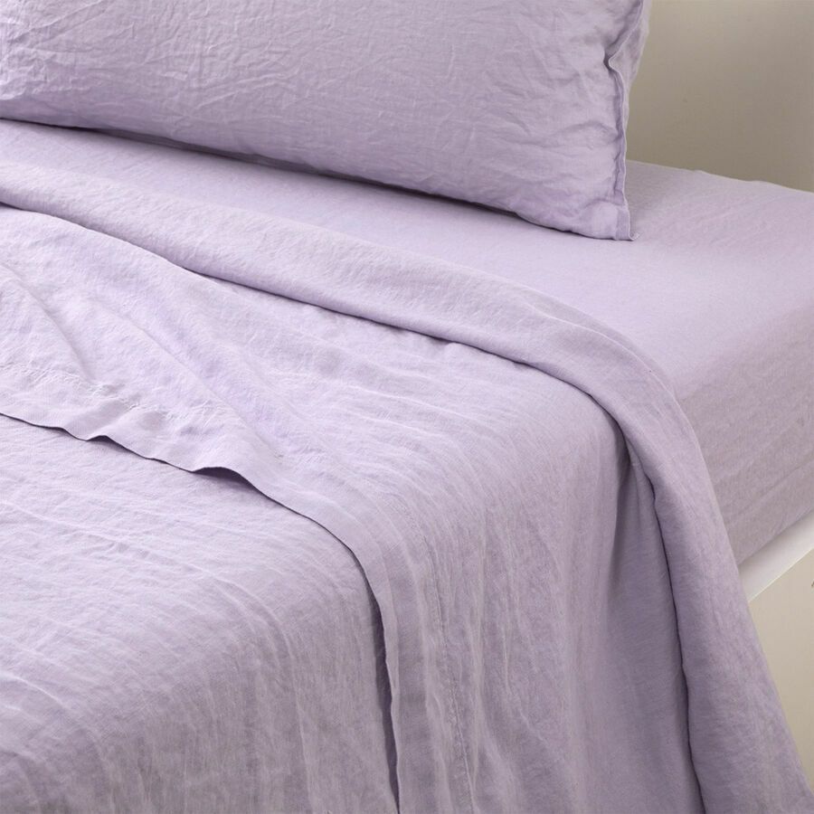 Un lit avec des draps et des oreillers violets dessus