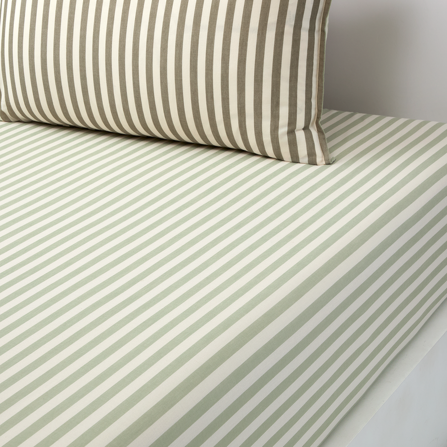 Linge de lit rayé beige et blanc avec oreiller assorti sur un lit bien fait