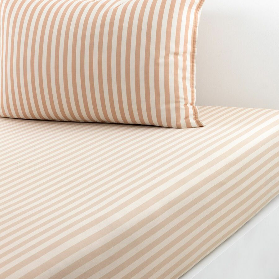 Linge de lit à rayures beiges et blanches avec oreiller assorti sur un lit