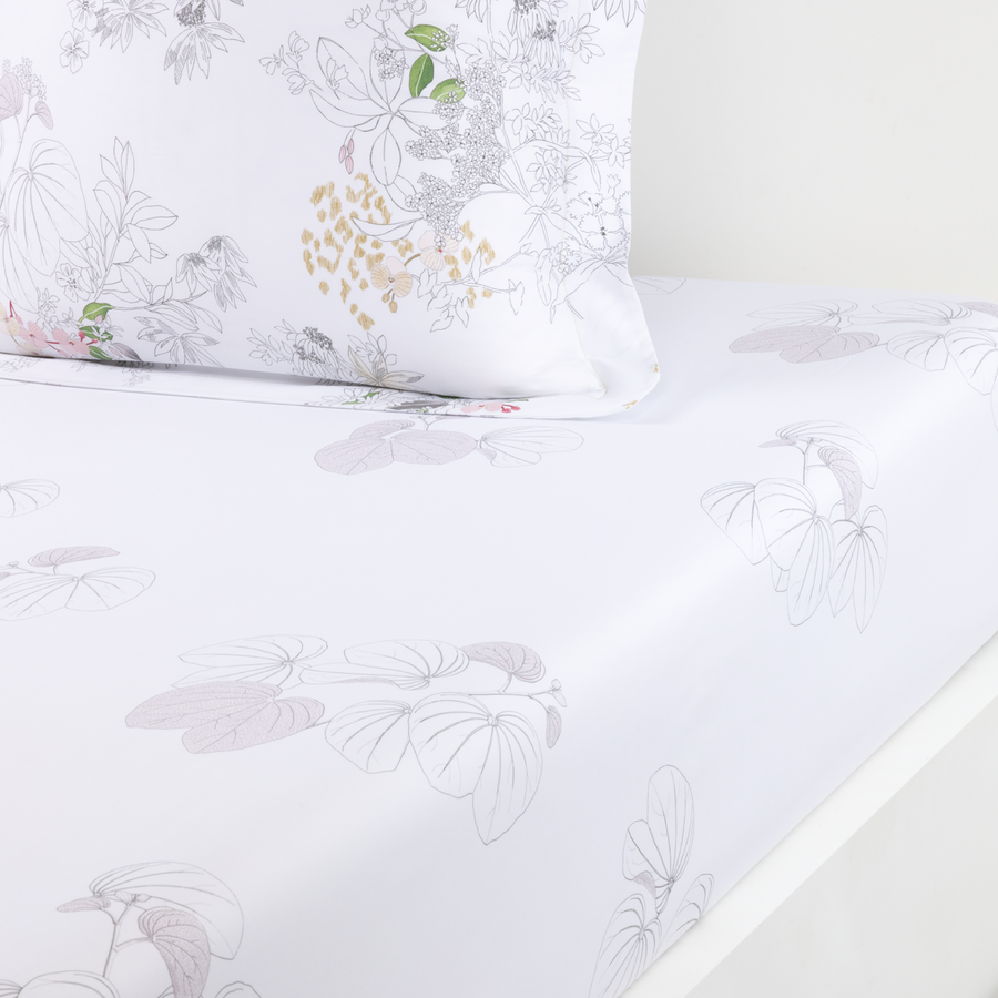 Drap-housse blanc orné d'un motif botanique et d'oiseaux subtil et délicat dans des tons doux de gris, de rose et de vert.