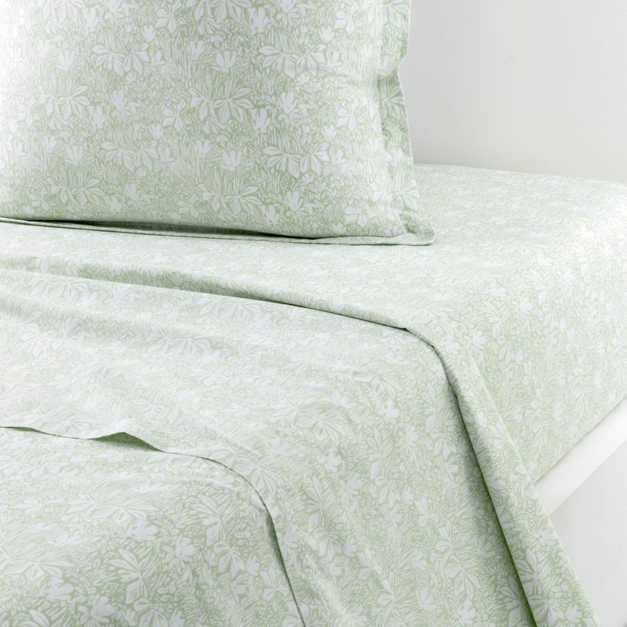 Un ensemble drap et taie d'oreiller vert clair orné d'un motif floral botanique blanc.