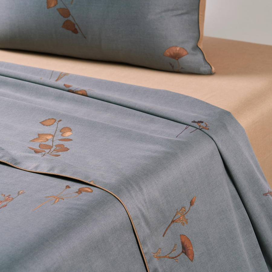 Un lit avec un oreiller et une couverture avec des feuilles dessus