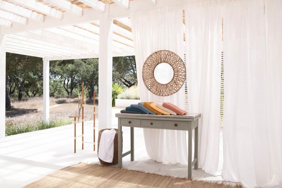 Une table avec un miroir dessus dans une pièce avec des rideaux blancs.