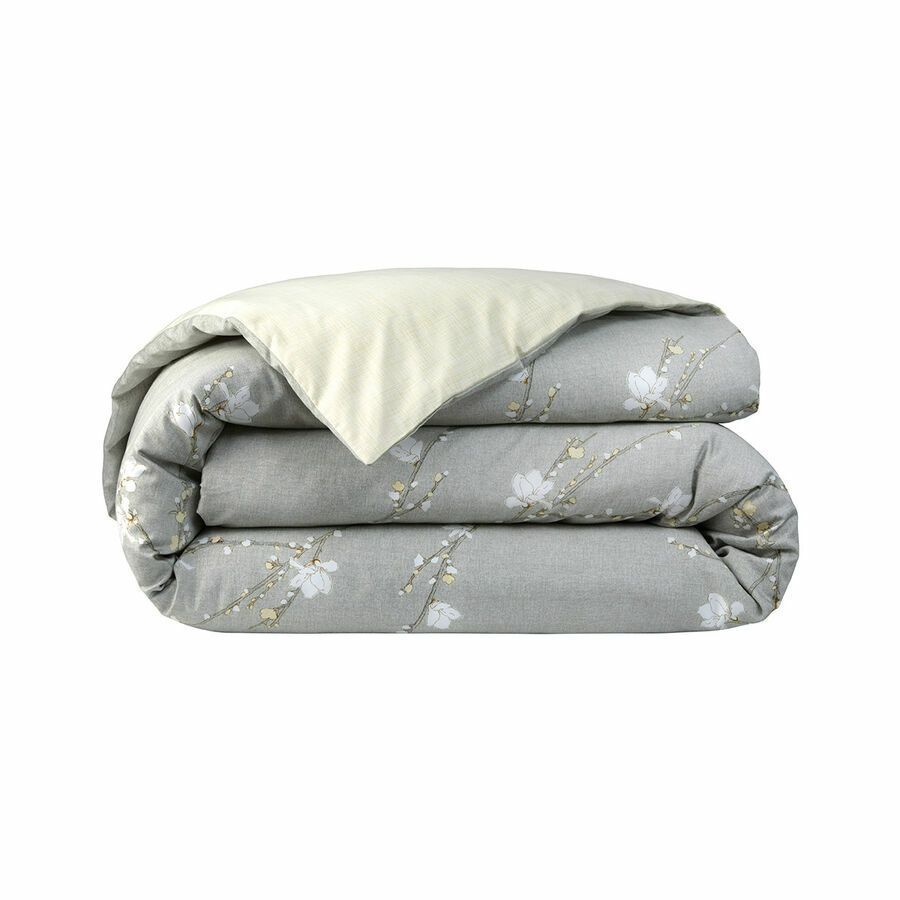 Une couette grise avec des fleurs blanches dessus est empilée les unes sur les autres sur un fond blanc.