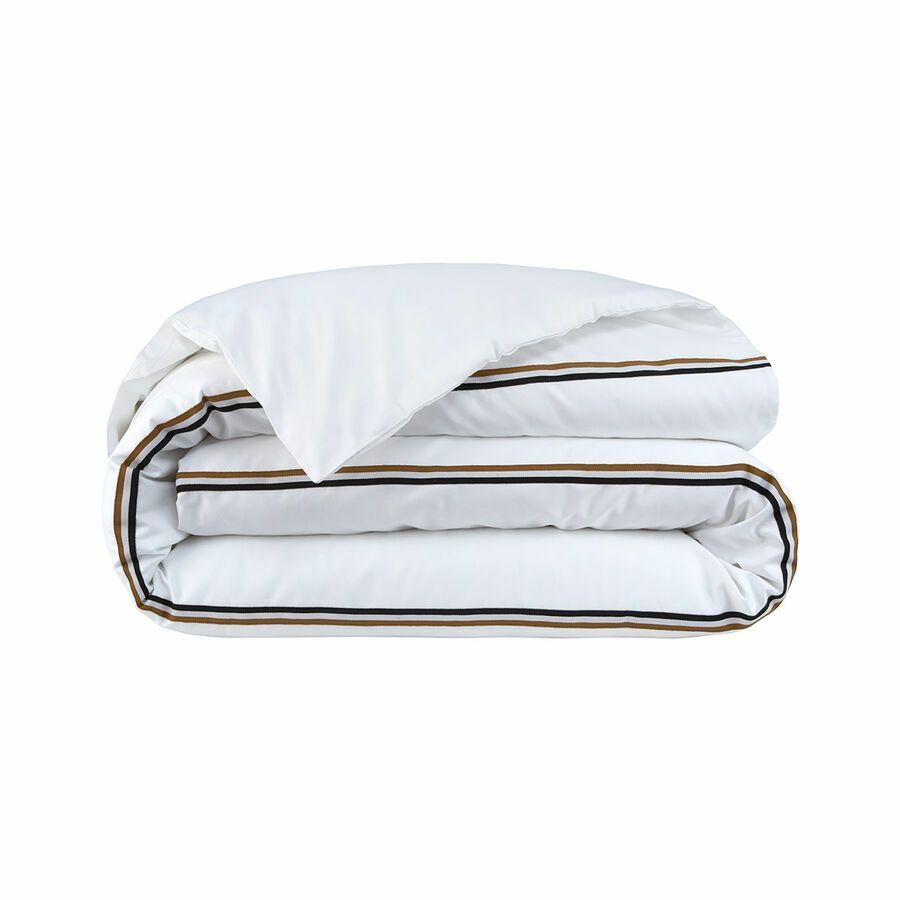 Une couette blanche avec des rayures marron dessus est empilée les unes sur les autres sur un fond blanc.