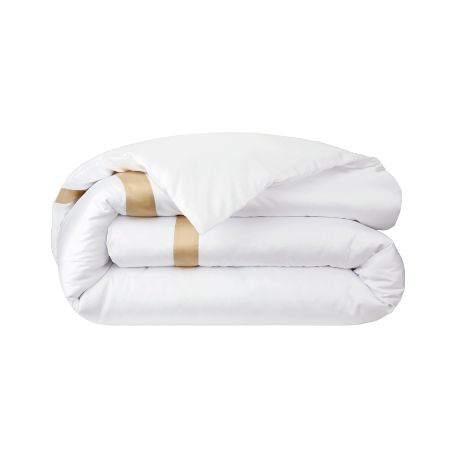 Couette blanche pliée avec détail à rayures dorées.