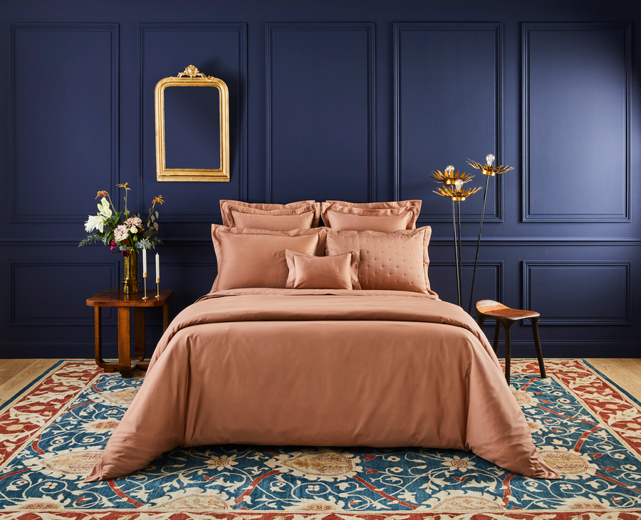 Une chambre avec un lit, un tapis, un miroir et des murs bleus.