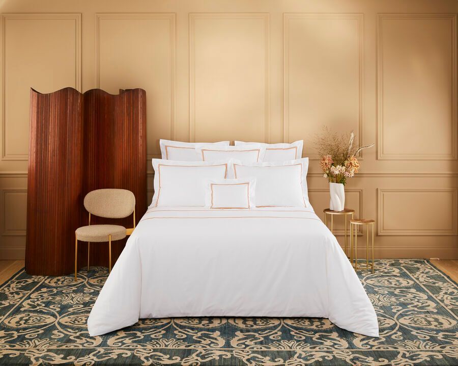 Il y a un lit avec des draps blancs et des oreillers dans la chambre.