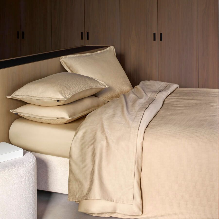Une chambre moderne avec un lit paré de draps couleur crème, d'oreillers empilés et un mur en lambris.