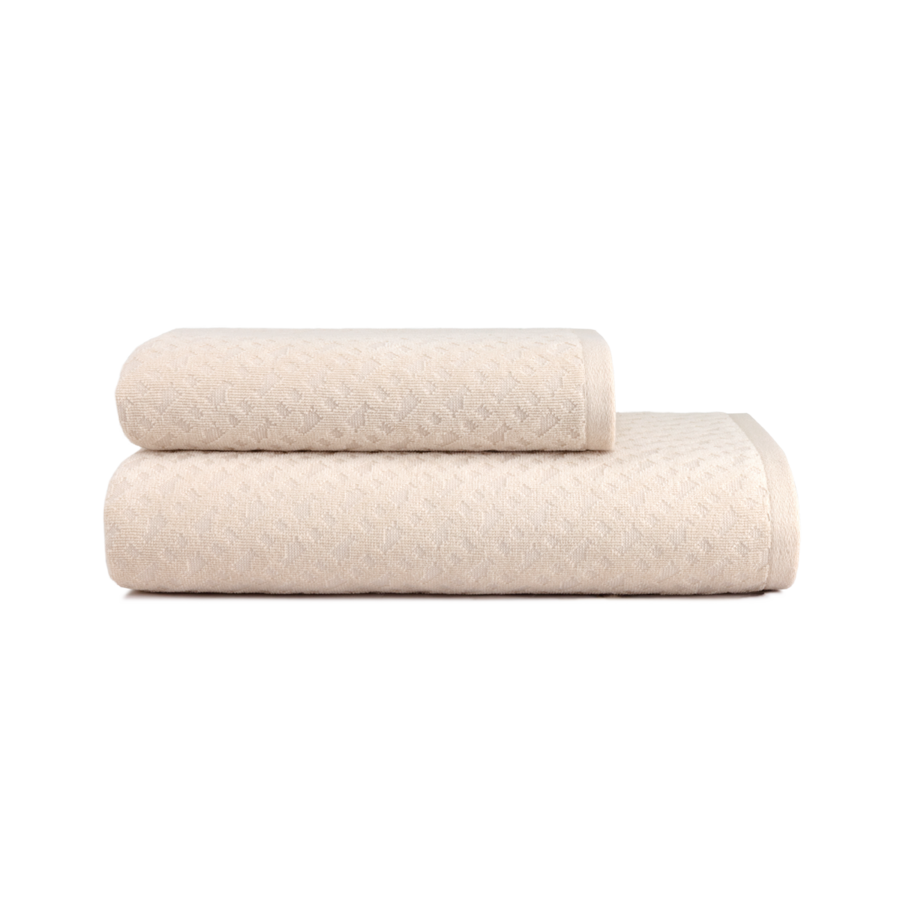 Deux serviettes de bain beiges texturées, soigneusement pliées, se détachent sur un fond blanc uni.