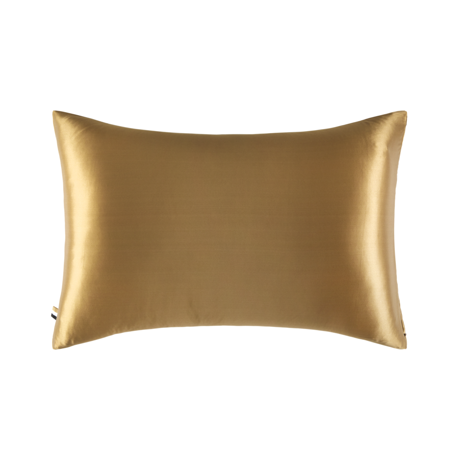 Un coussin en satin doré sur fond blanc.
