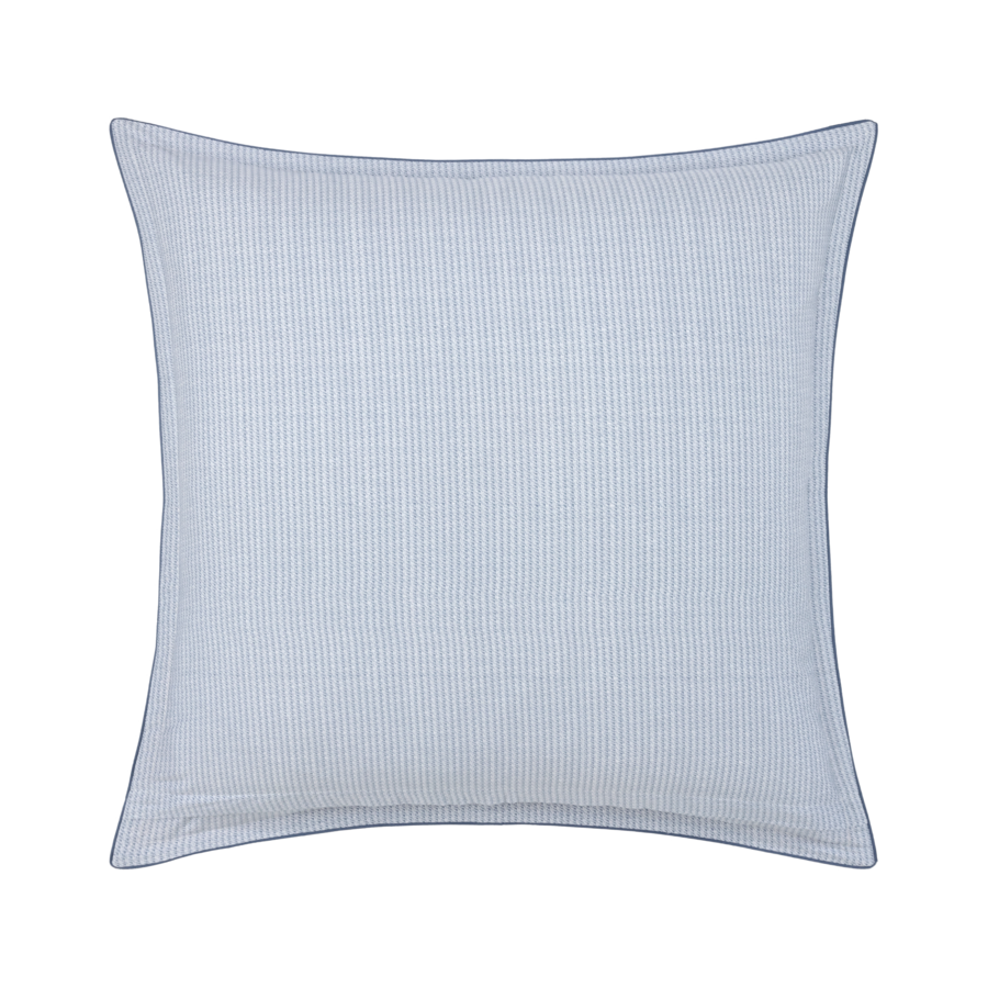 Un coussin rayé bleu et blanc sur fond blanc.