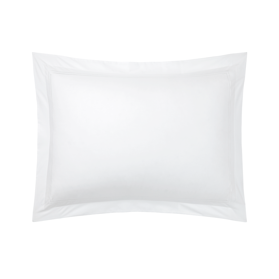 Un oreiller blanc est posé sur un lit sur un fond blanc.