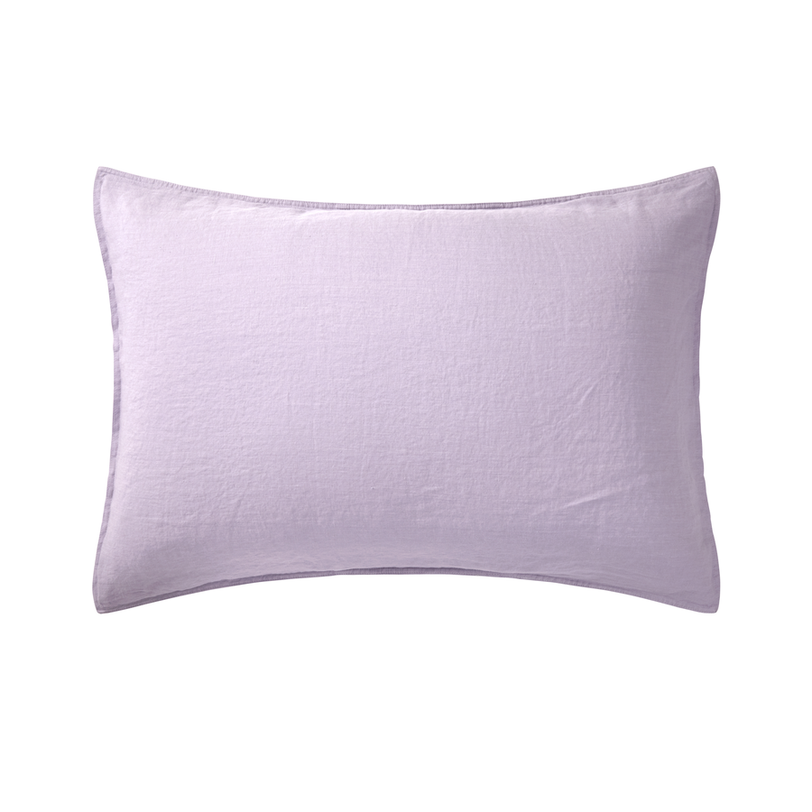 Un oreiller violet est posé sur une surface blanche.