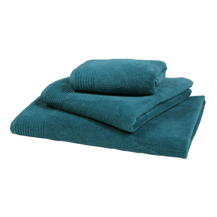 Trois serviettes bleu sarcelle sont empilées les unes sur les autres sur un fond blanc.