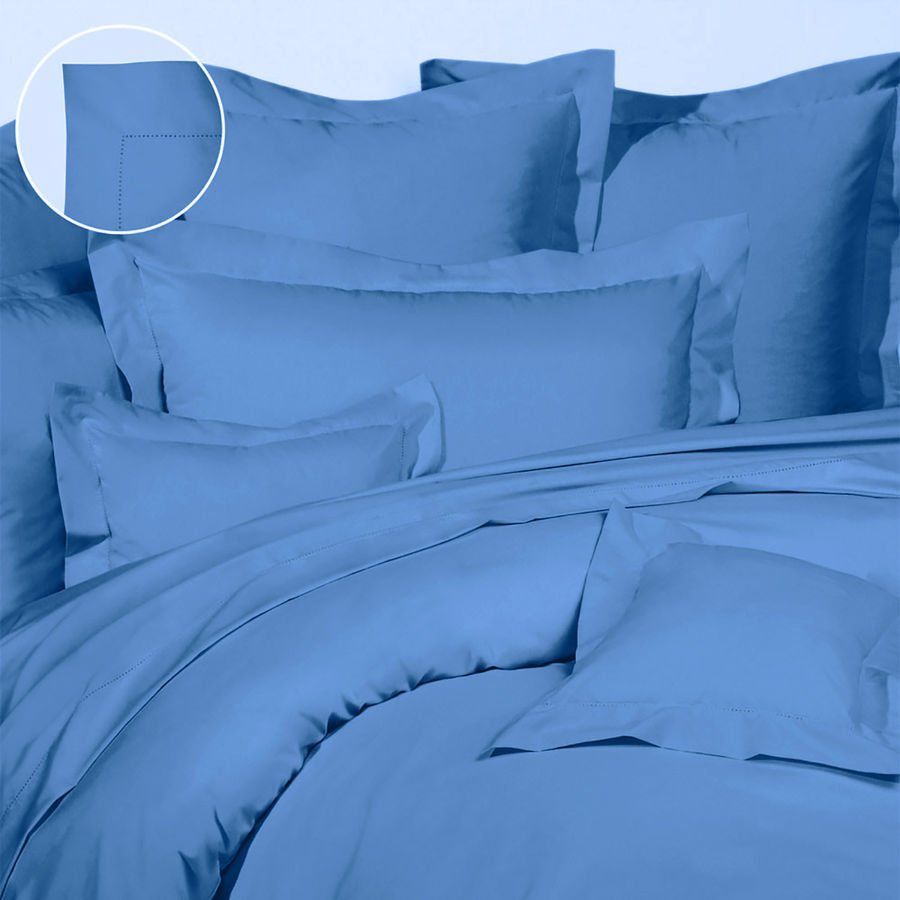 Un lit avec une couette bleue et des oreillers dessus