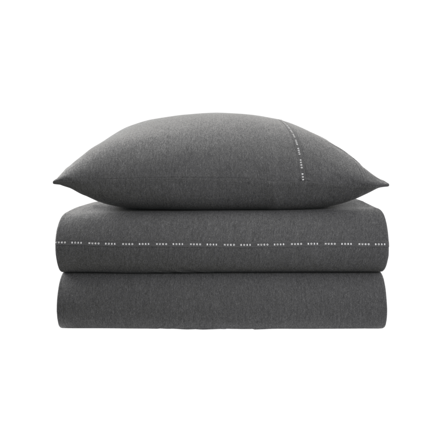 Une pile de draps et d'oreillers gris sur fond blanc