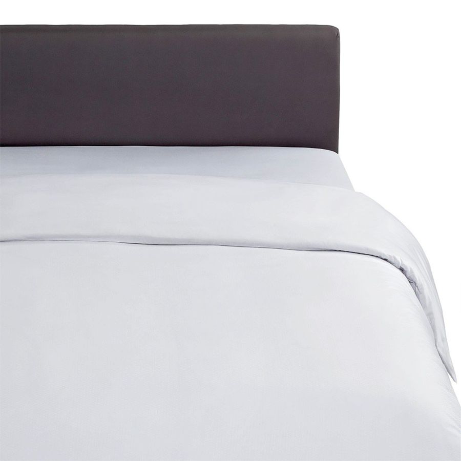 Un lit avec une couette blanche et une tête de lit grise