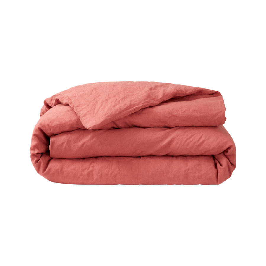 Une couette rose est empilée les unes sur les autres sur un fond blanc.