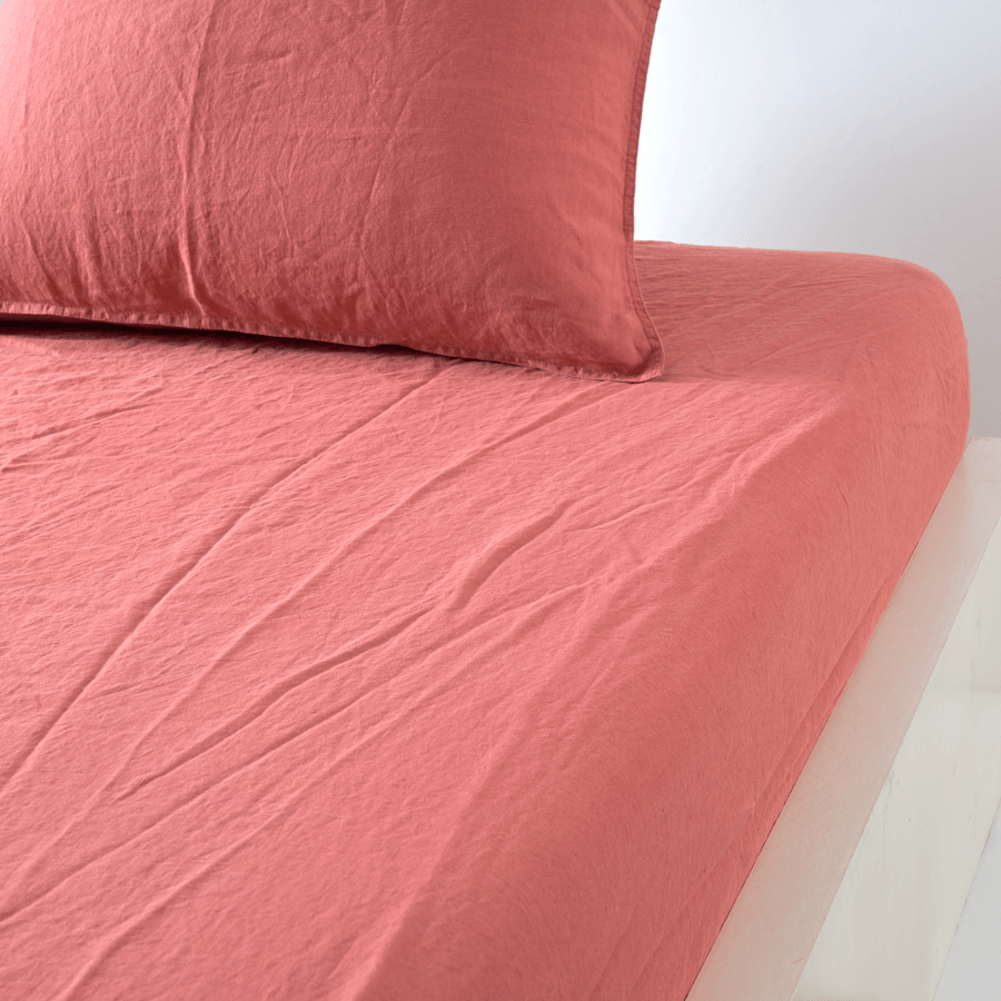 Un lit avec une couette rose et des oreillers dessus.