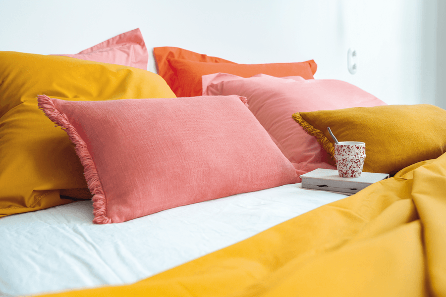 Un lit avec beaucoup d'oreillers et une tasse dessus.