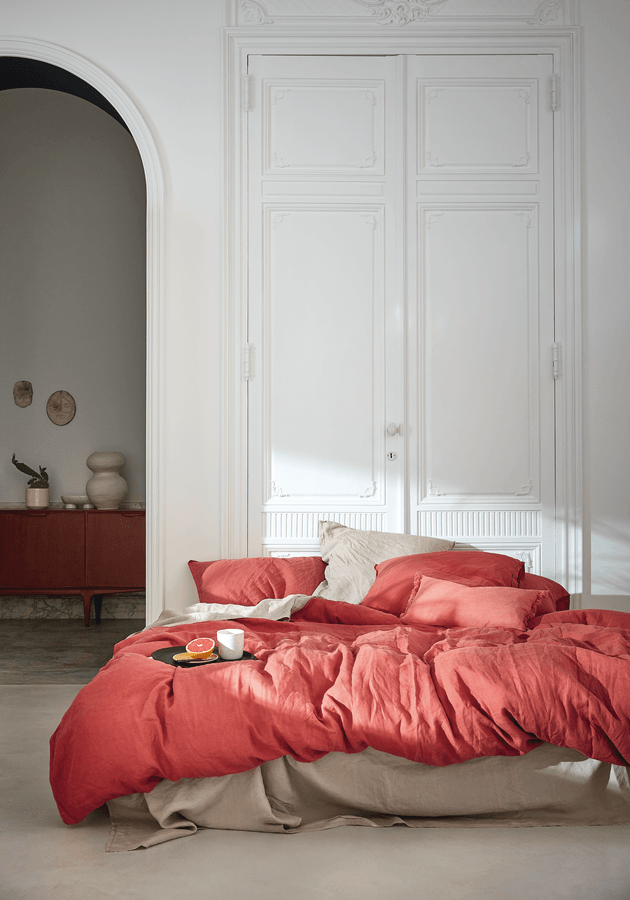 Un lit avec une couette rouge et des oreillers dans une chambre.