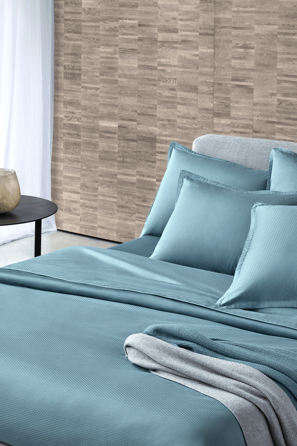 Un lit avec des draps et des oreillers bleus dans une chambre.
