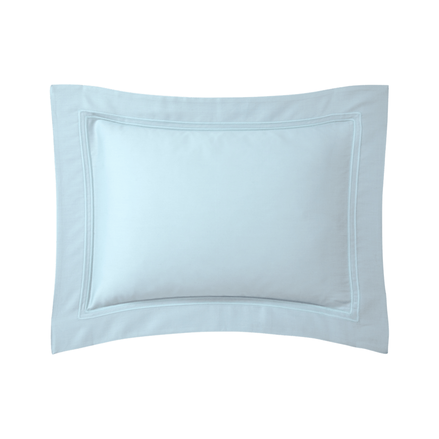 Un coussin bleu clair avec une bordure blanche sur fond blanc.