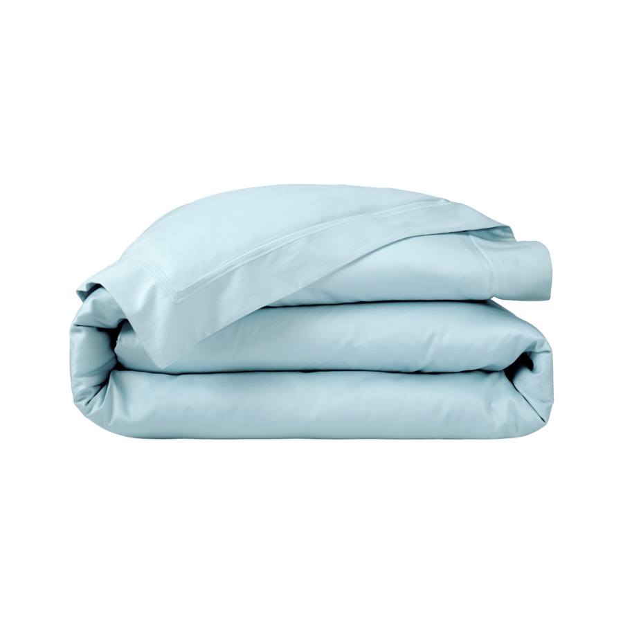 Une couette bleu clair est empilée les unes sur les autres sur un fond blanc.