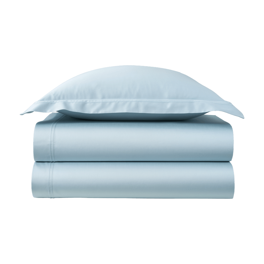 Une pile de draps et d'oreillers bleu clair sur fond blanc