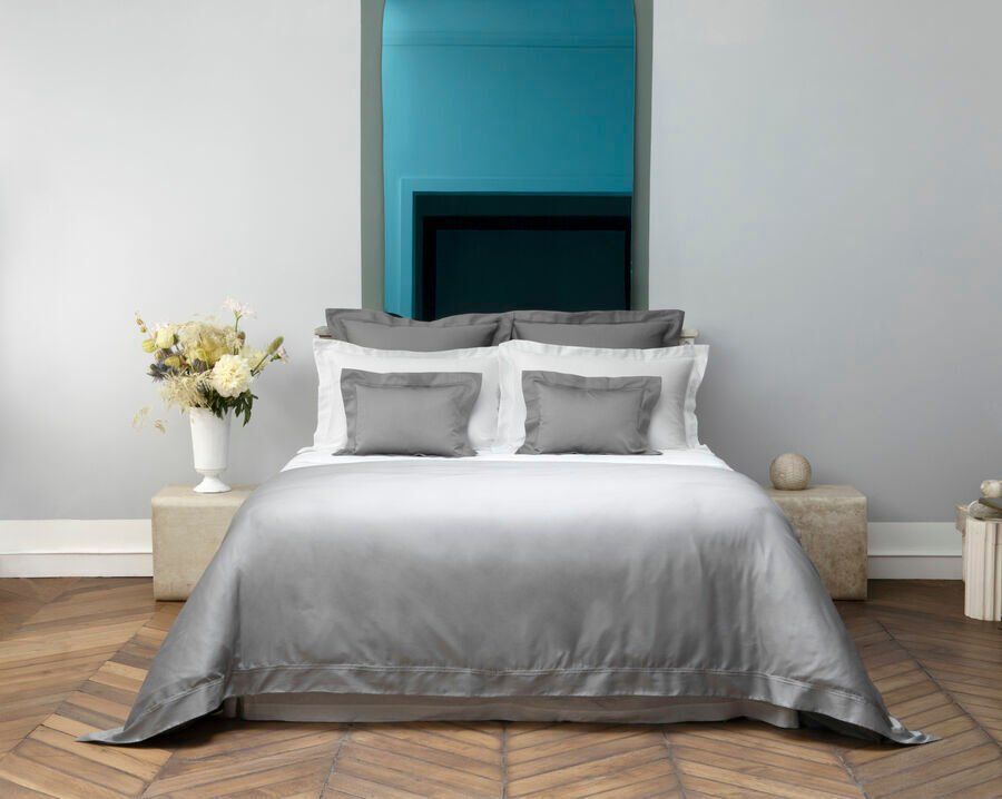 Un lit avec une couette et des oreillers gris dans une chambre.