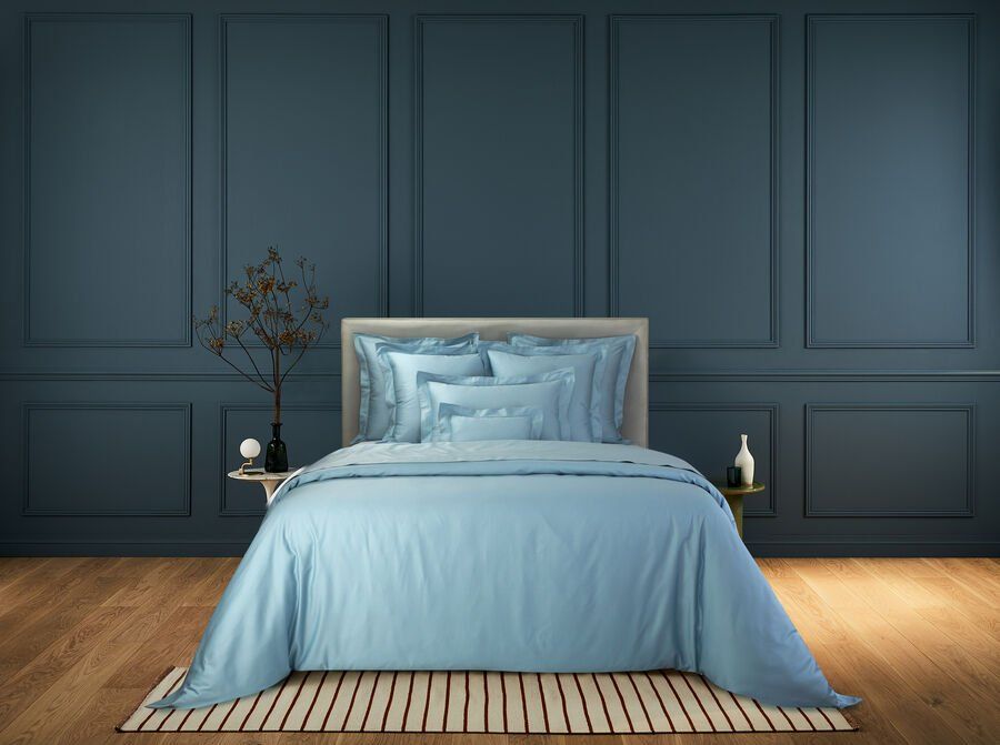 Une chambre avec des murs bleus et un lit avec des draps et des oreillers bleus.
