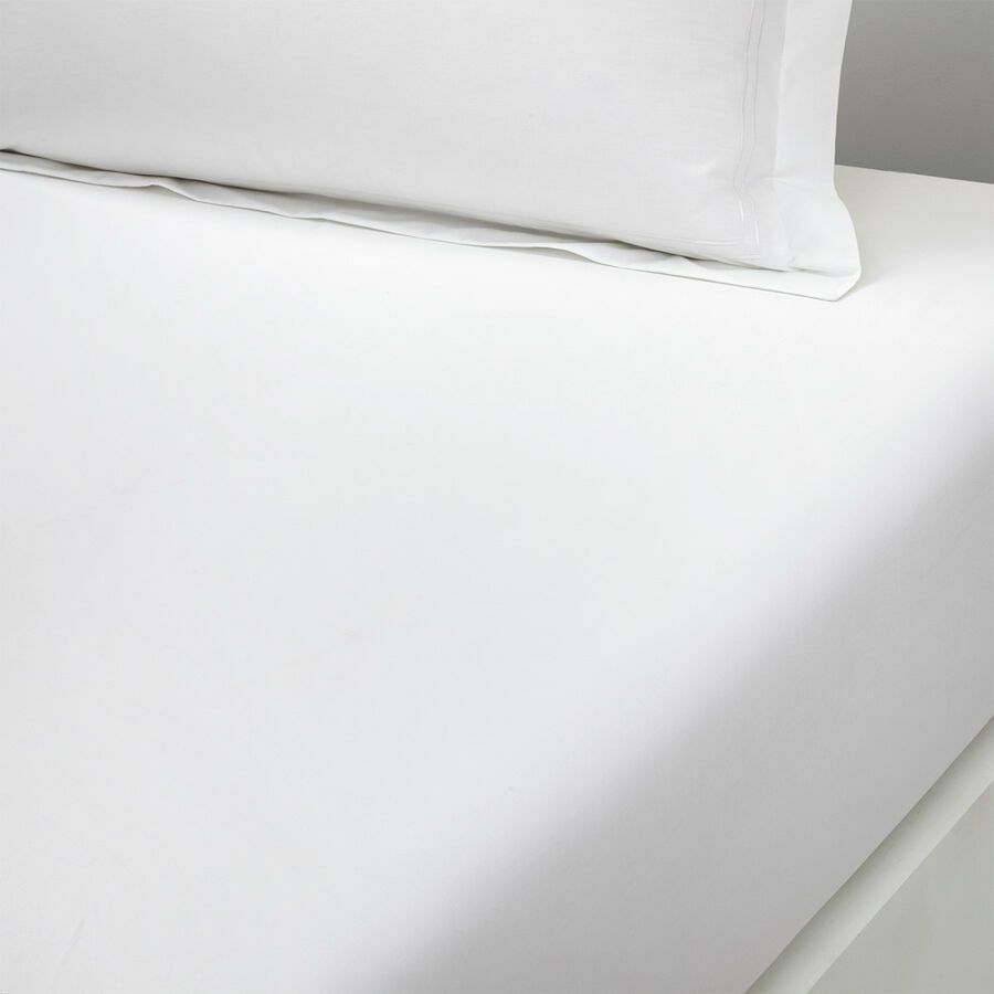 Un lit avec des draps blancs et des oreillers dessus.
