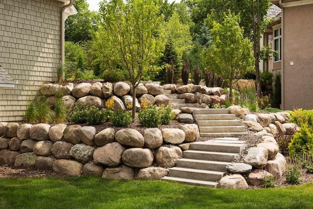 A stone wall with stairs leading up to a house.