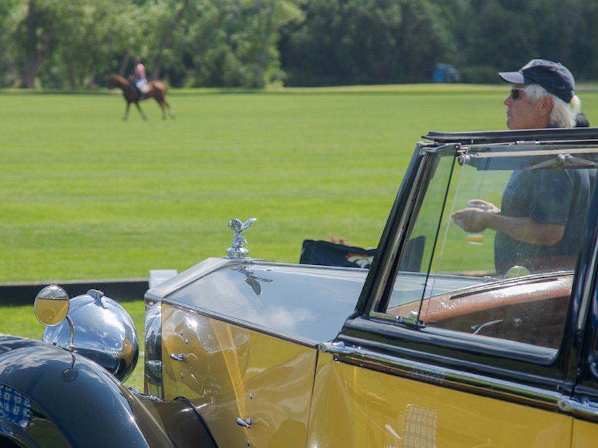 A man is sitting in a car watching a polo match