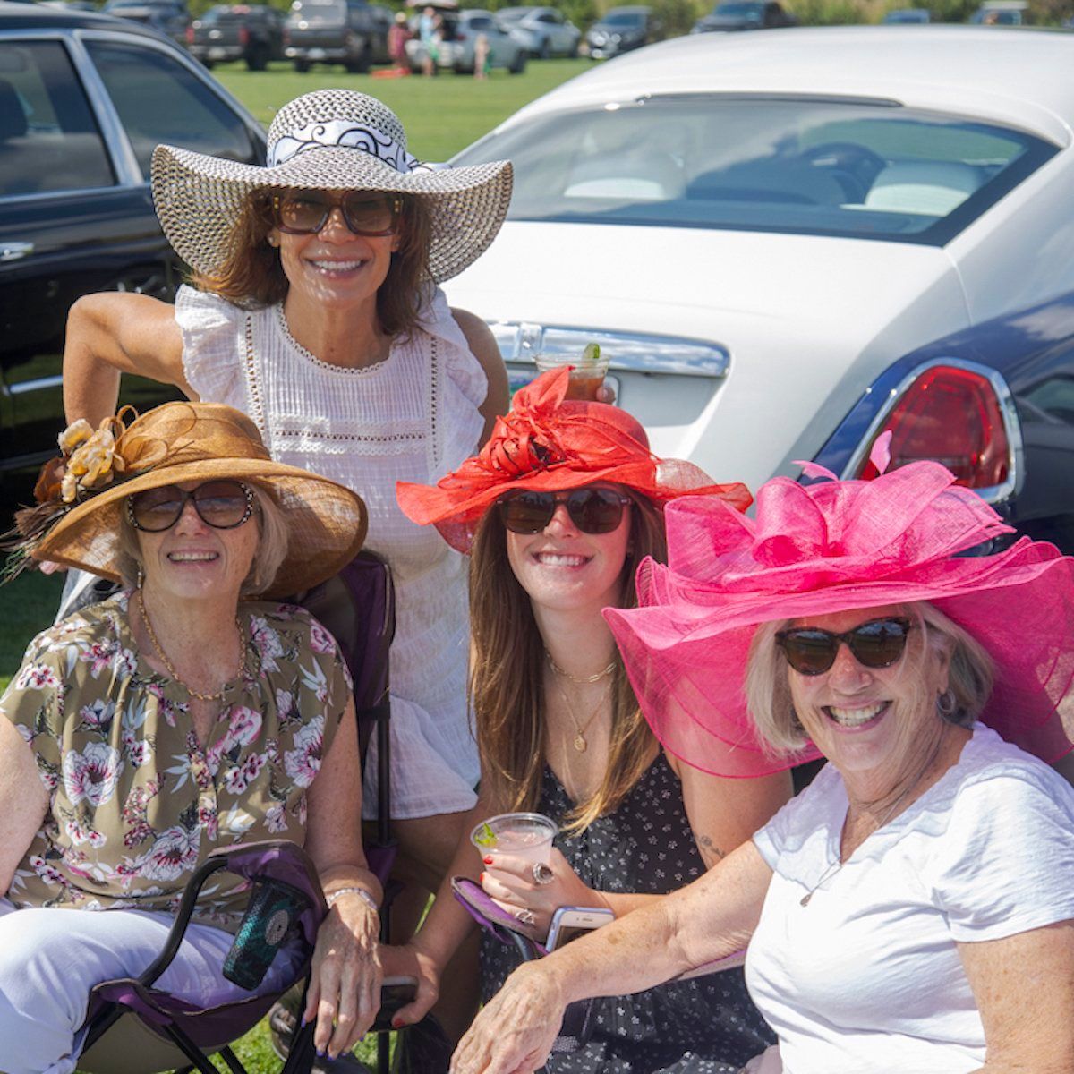 Four women wearing hats and sunglasses are posing for a picture
