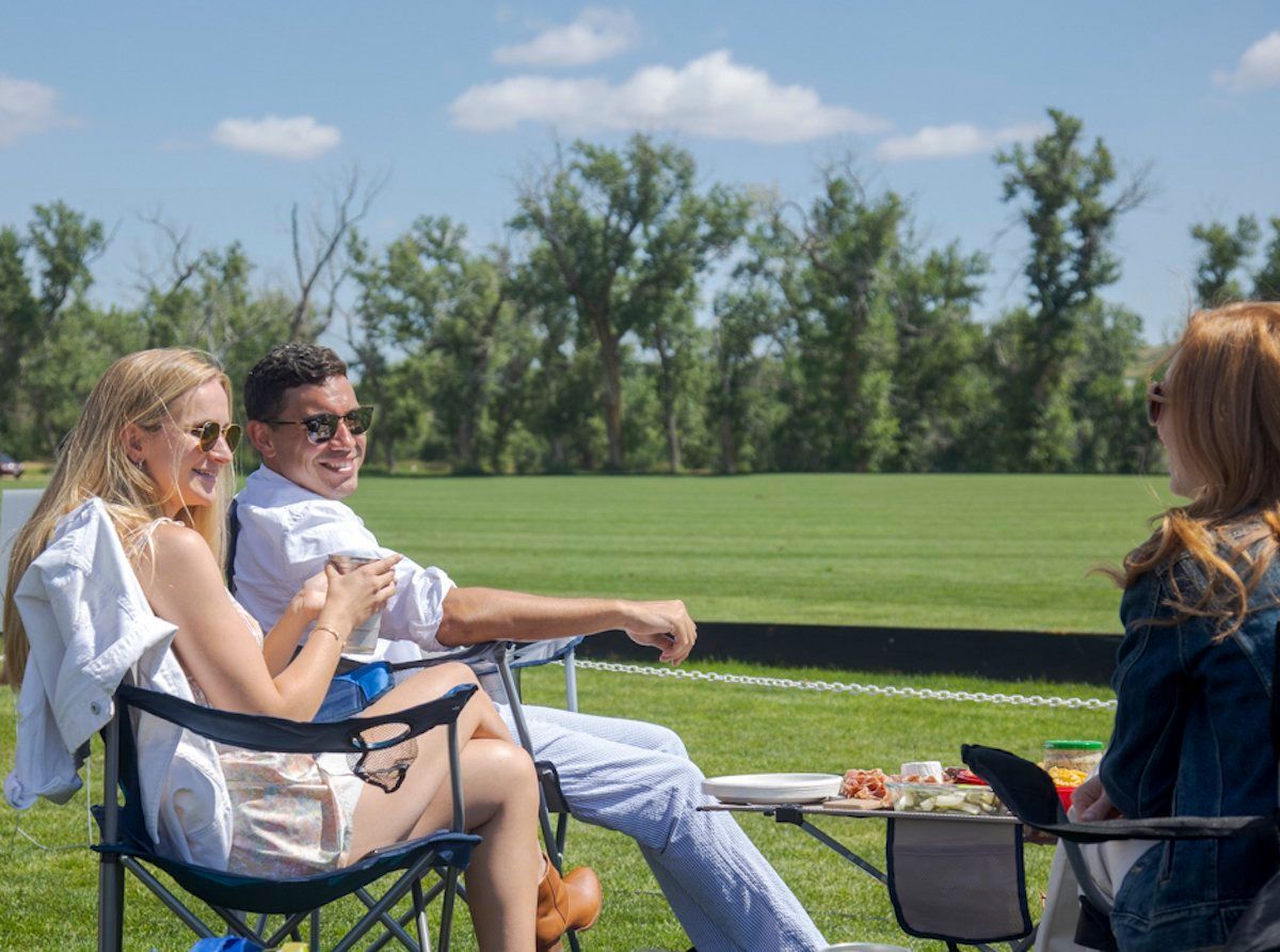 A group of people are sitting in folding chairs in a field.