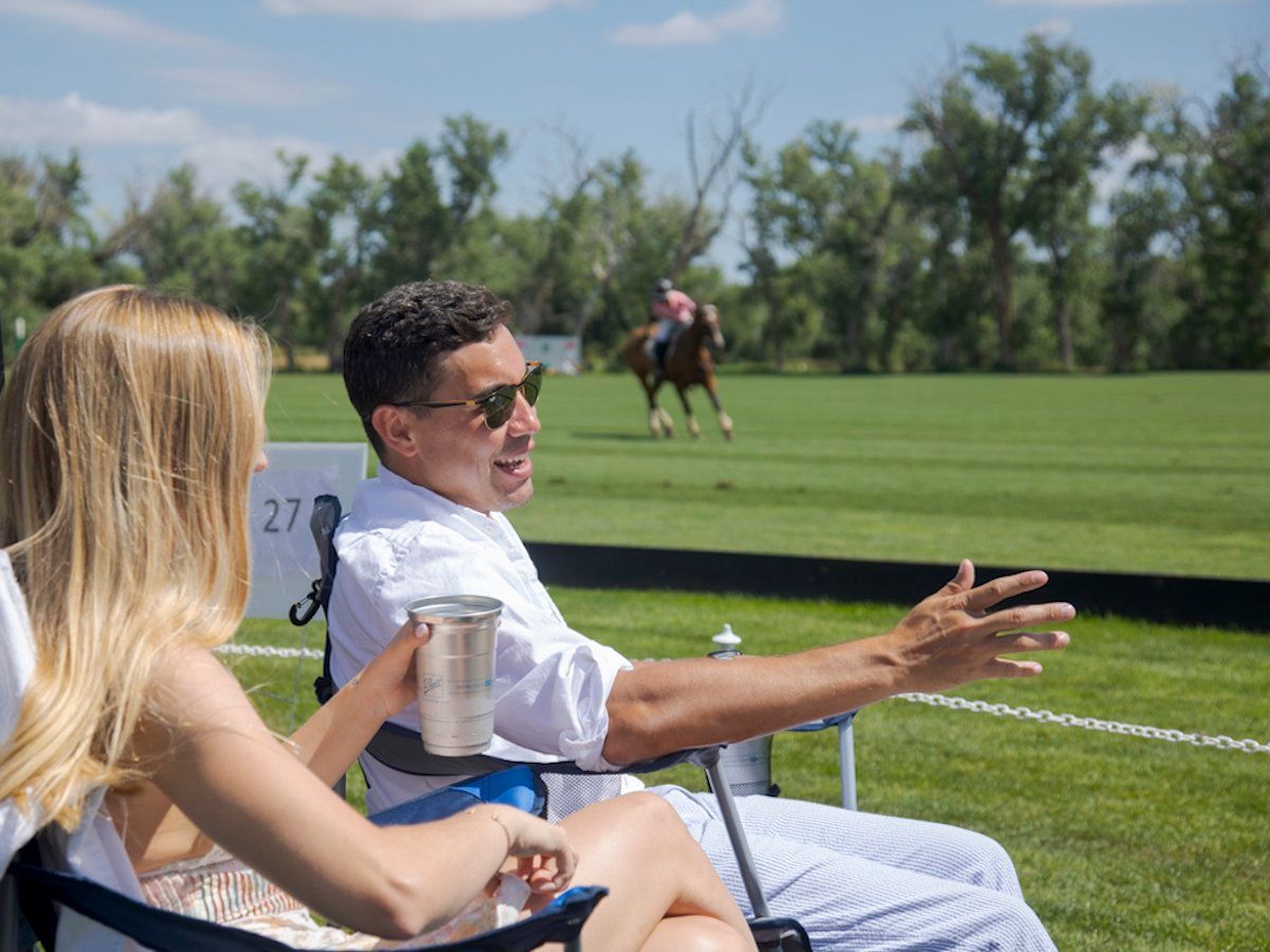 A man and a woman are sitting in chairs watching a polo game.