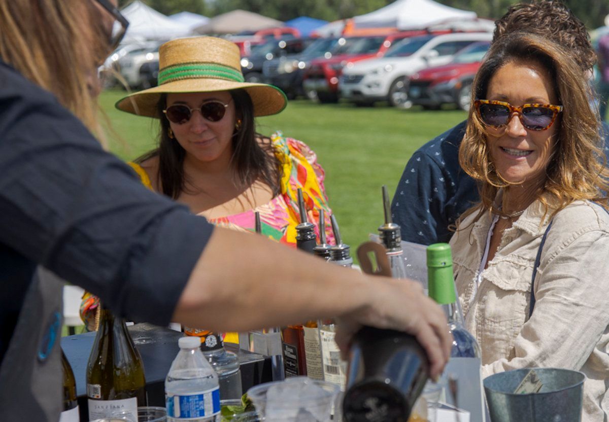 A man is pouring a drink into a glass for a woman.