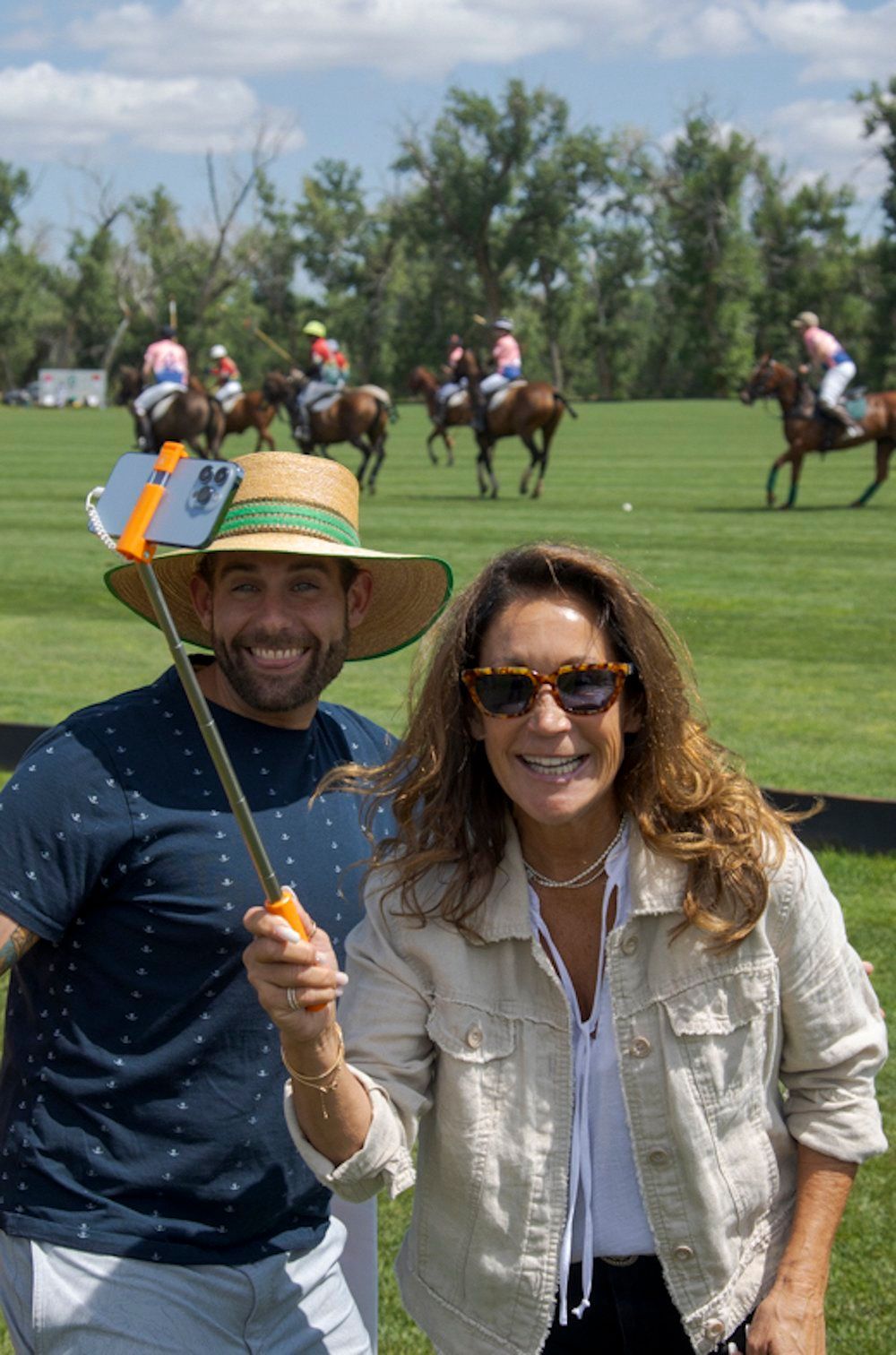 A man and a woman are posing for a picture on a polo field.