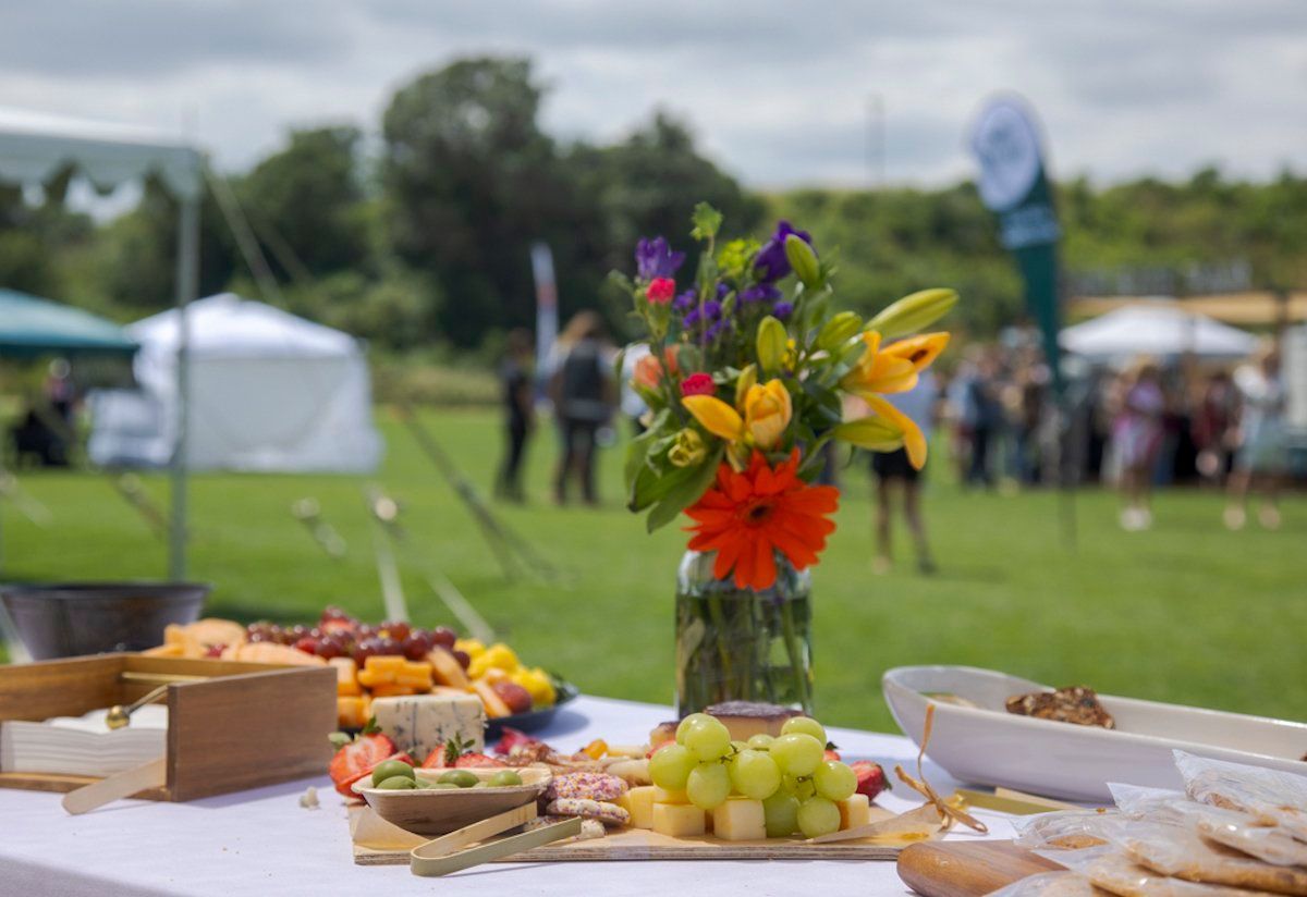 A table with a vase of flowers and a variety of food on it.