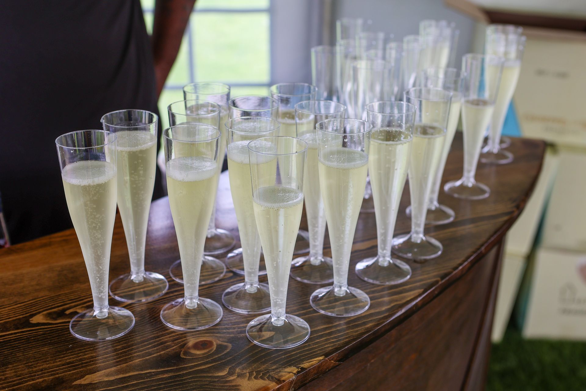 Champagne flutes filled with bubbly, lined up on a wooden bar, ready to serve.