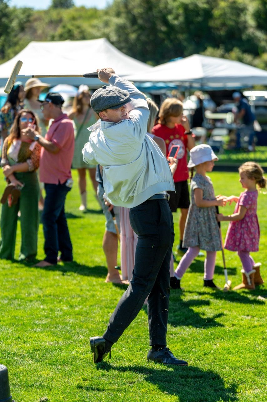 A man is swinging a golf club in a field while a group of people watch.