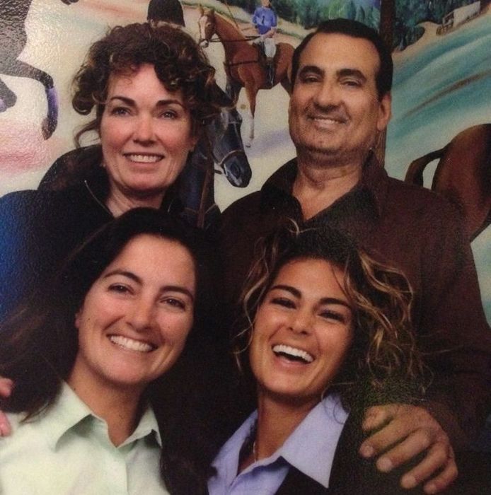 A group of people posing for a picture with horses in the background