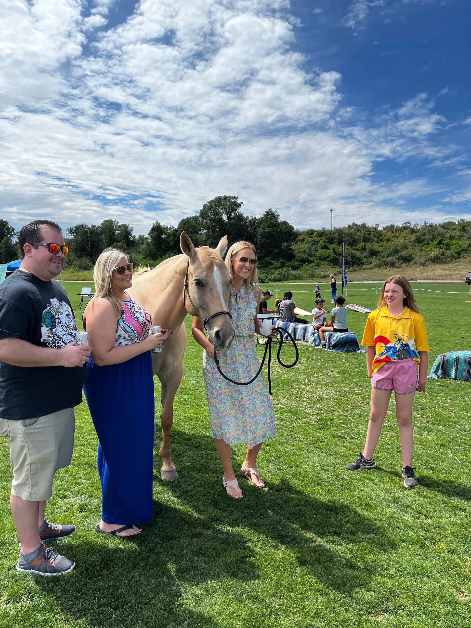 A group of people standing next to a horse in a field.